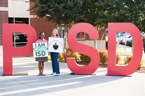 Patricia Hempstead and Deni Bleggi standing by PISD sign 
